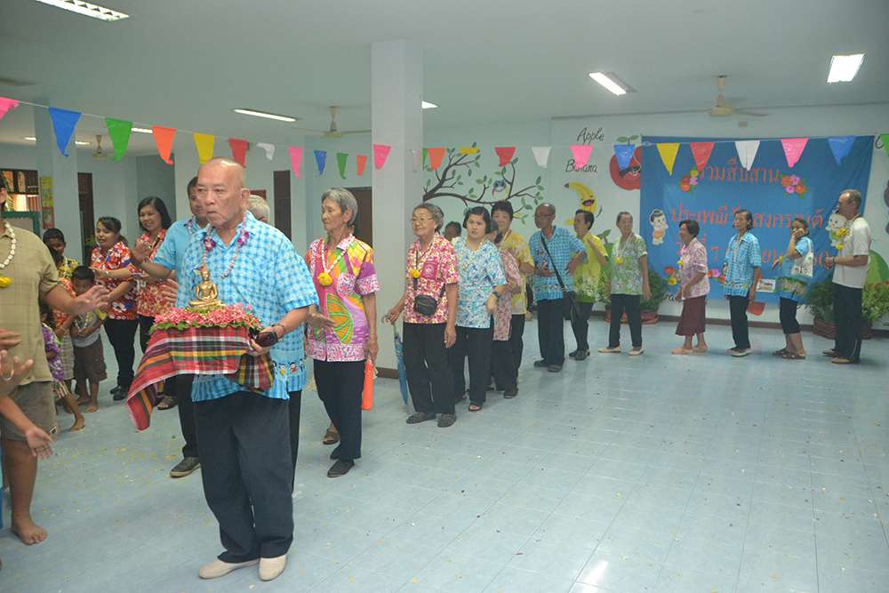 A respected elder begins the procession to bring out the Buddha statue to a more convenient place for everyone to take part in bathing the Buddha image.