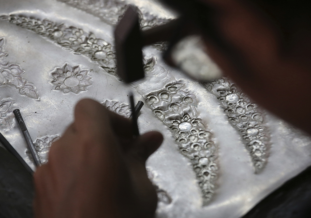 A student volunteer hammers designs into silver plates to decorate the royal crematorium. (AP Photo/Sakchai Lalit)