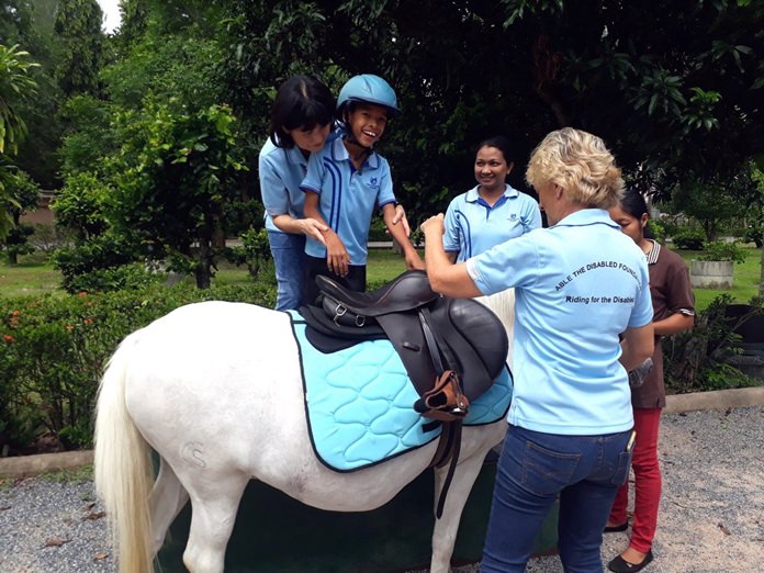 There are many hands to help the child to sit on the pony, this one with a new blanket.