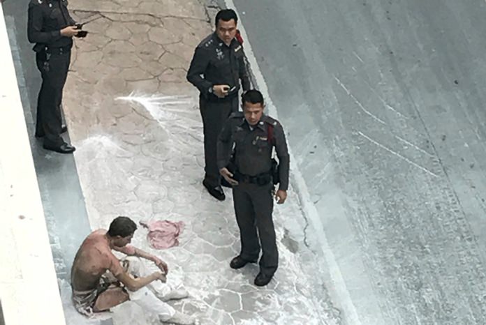 An unidentified man sits on the ground after he set himself on fire outside the Iranian Embassy Friday, May 19, in Bangkok. (Photo via AP)