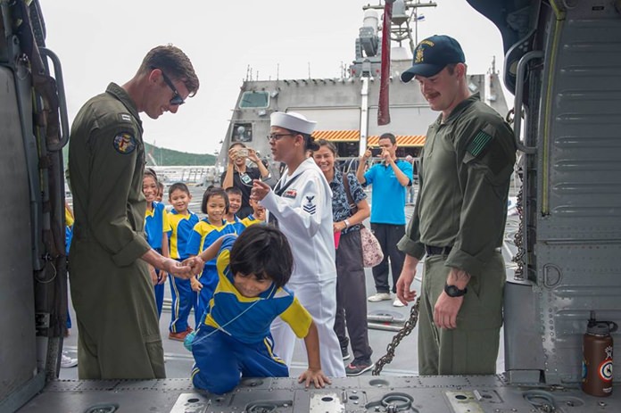 Sailors aboard littoral combat ship USS Coronado (LCS 4) help children inside an MH-60S Seahawk.