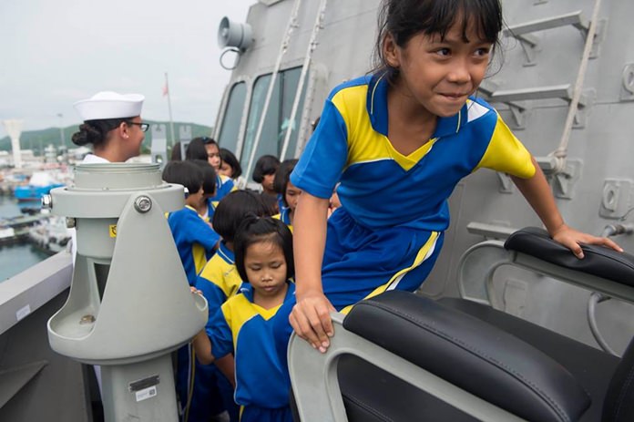 A child from a local school climbs in the Captain’s chair on the bridge wing aboard littoral combat ship USS Coronado (LCS 4).