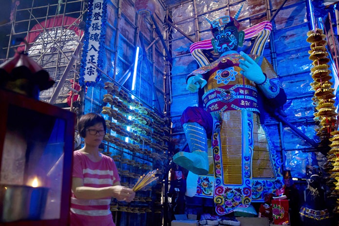 A woman burns joss sticks in front of a paper reproduction of the “Ghost King” at a makeshift altar during the “Hungry Ghost Festival” in Hong Kong. In traditional Chinese belief, the seventh month of the lunar year is reserved for the Hungry Ghost festival, or Yu Lan, a raucous celebration marked by feasts and music. (AP Photo/Kin Cheung)