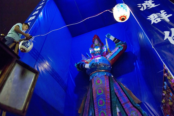 A man hangs a lantern in front of a paper reproduction of the “Ghost King”. (AP Photo/Kin Cheung)