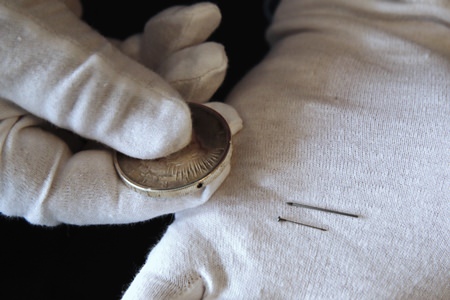 A silver dollar with a hole for a hidden suicide pin is one of Melton’s donations to the International Spy Museum from his collection of spy objects. (AP Photo/Jacquelyn Martin)