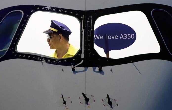 In this Wednesday, Sept. 20, 2017 file photo, a man wearing a pilot hat prepares to take a souvenir picture on a mock cockpit promoting the Airbus airliner at Aviation Expo China in Beijing. The expo features as many as 300 foreign and local exhibitors showcasing their latest aviation products. (AP Photo/Andy Wong, File)