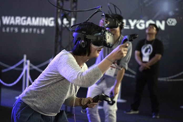 In this Thursday, Sept. 21, 2017 file photo, visitors try out a game with a virtual reality headset device at the Tokyo Game Show in Chiba, near Tokyo. The Japanese video game industry is finding its way out of the doldrums by adapting new technology for decades-old titles. And that energy was evident at the annual game show. (AP Photo/Eugene Hoshiko, File)