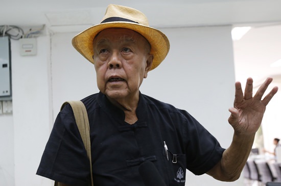 Social critic Sulak Sivaraksa talks to reporters at a police station before going to a military court in Bangkok, Monday, Oct. 9. (AP Photo/Sakchai Lalit)