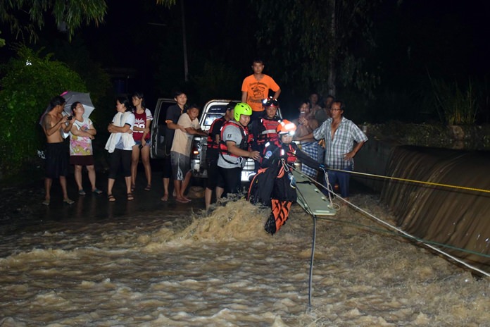 Two teams of paramedics use ropes to pull two men to shore after their SUV was swept off a river road in Khao Maikaew.