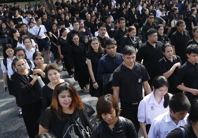 Mourners hold a portrait of late HM the late King Bhumibol Adulyadej in line to pay their respects to the Royal Urn outside the Grand Palace for last day of viewing in Bangkok, Thursday, Oct. 5, 2017. HM the late King Bhumibol Adulyadej died on Oct. 13 last year at age 88 after seven decades on the throne. The royal cremation is scheduled on Oct. 26, 2017. (AP Photo/Sakchai Lalit)