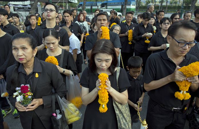 Mourners line up in front of a portrait of the late King Bhumibol Adulyadej to pay respects outside the Grand Palace in Bangkok, Thailand, Friday, Oct. 13, 2017. (AP Photo/Gemunu Amarasinghe)