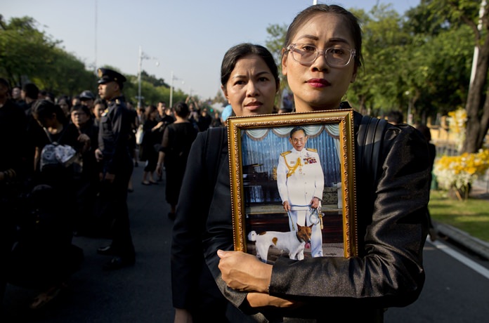 Thai mourners, carrying a portrait of HM late King Bhumibol Adulyadej gather in front of a replica of the royal crematorium in Bangkok, Thursday, Oct. 26. (AP Photo/Gemunu Amarasinghe)
