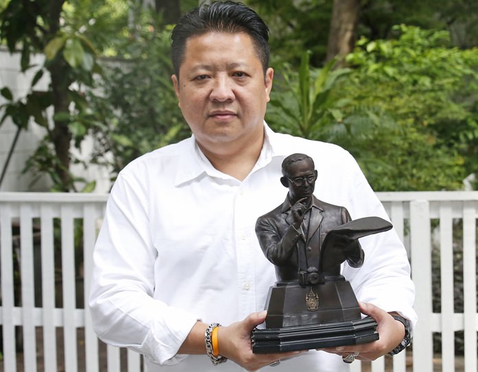 Somboon Chaisittiporn, 48, a Thai businessman, poses with a bronze statue of the late Thai King Bhumibol Adulyadej. (AP Photo/Sakchai Lalit)