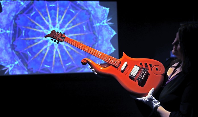 An employee shows the ‘Orange Cloud Guitar’ once played by artist Prince, at the ‘My Name is Prince’ exhibition at the O2 Arena in London, Thursday, Oct. 26. (AP Photo/Frank Augstein)