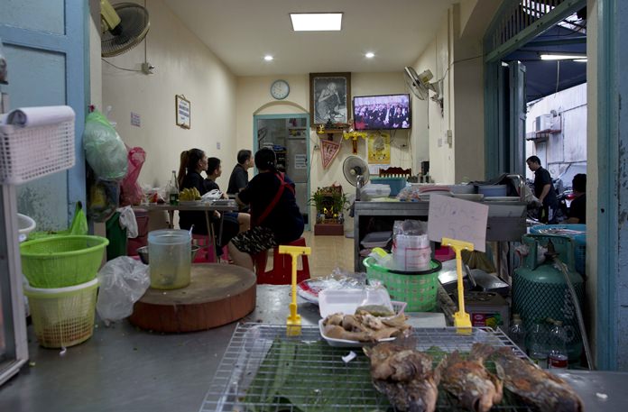 A Thai restaurant owner and customers watch a live television broadcast of the funeral of late Thai King Bhumibol Adulyadej. (AP Photo/Gemunu Amarasinghe)