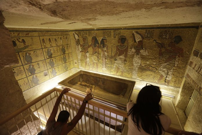 In this Thursday, Nov. 5, 2015, file photo, tourists look at the tomb of King Tut as it is displayed in a glass case at the Valley of the Kings in Luxor, Egypt. (AP Photo/Amr Nabil)