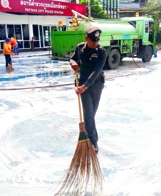 Pol. Lt. Saranpong Maithong, chief crime suppression officer leads officers in cleaning up around Pattaya Police Department.