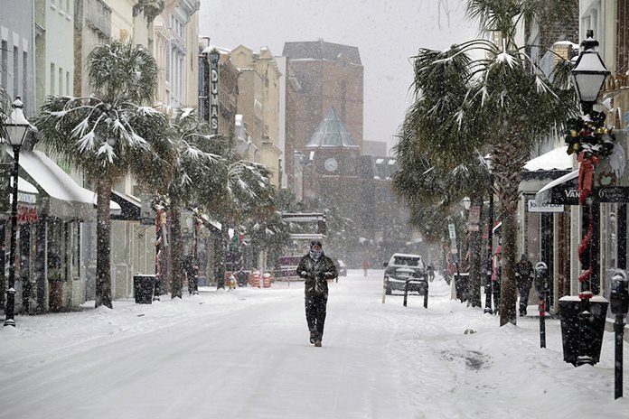 A person walks in the snow on King Street in Charleston, S.C., Wednesday, Jan. 3, 2018. A brutal winter storm smacked the coastal Southeast with a rare blast of snow and ice, hitting parts of Florida, Georgia and South Carolina with their heaviest snowfall in nearly three decades. (Matthew Fortner/The Post And Courier via AP)