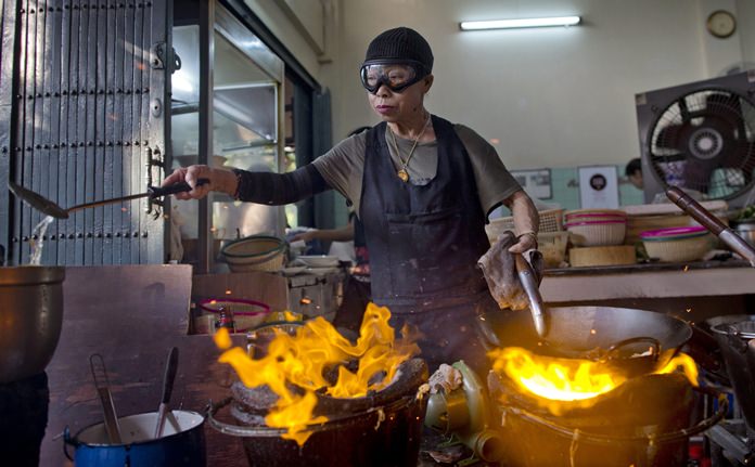 Thai cook Supinya Jansuta, 72, better known as “Jay Fai,” wearing goggles, cooks with two flaming woks at her eatery in Bangkok. After spending more than three decades cooking in an unassuming outdoor kitchen, Jay Fay has been propelled to international culinary stardom by having her restaurant awarded a Michelin star. (AP Photo/Gemunu Amarasinghe)
