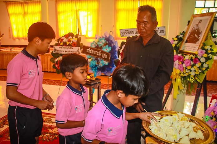Children under the care of HHN Foundation Thailand present sandalwood flowers to their senior member who died.