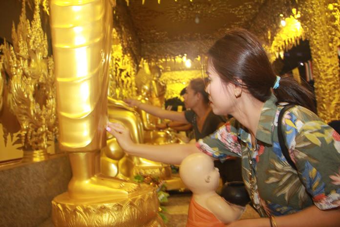 Families join in to paste gold leaf on Bhuddha images as a sign of devotion.