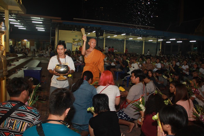 A monk blesses the congregation by sprinkling holy water over them.