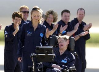 Astrophysicist Stephen Hawking is assisted off the tarmac at the Kennedy Space Center by his caregiver, Monica Guy, as he is applauded by members of the flight crew after completing a zero-gravity flight, Thursday, April 26, 2007. (AP Photo/Peter Cosgrove, File)