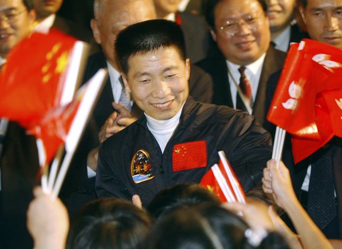 In this Oct. 31, 2003, file photo, school children wave Chinese and Hong Kong flags as they welcome China’s first astronaut Yang Liwei, center. China says it plans to begin recruiting civilian astronauts for its military-backed space program. (AP Photo/Anat Givon, File)
