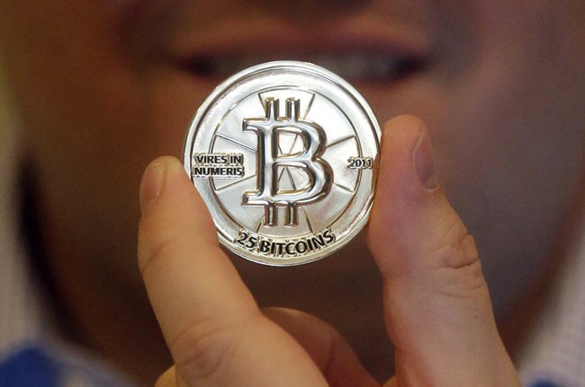 In this April 3, 2013 photo, Mike Caldwell, a 35-year-old software engineer, holds a 25 Bitcoin token at his shop in Sandy, Utah. (AP Photo/Rick Bowmer)