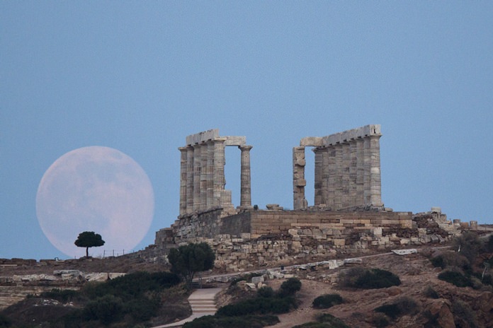 In this June 20, 2016 file photo, the full moon rises near the ancient marble Temple of Poseidon at Cape Sounion, southeast of Athens. (AP Photo/Petros Giannakouris)