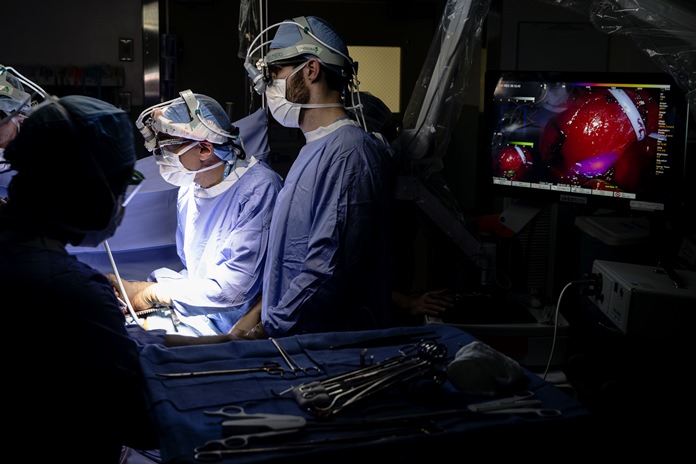 Dr. Sunil Singhal, second from right, directs a special camera to view a tumor in his patient made visible with a fluorescent dye, seen at monitor on right, at the Hospital of the University of Pennsylvania in Philadelphia, Tuesday, Jan. 23, 2018. Researchers are testing fluorescent dyes that make cancer cells glow to make them easier for surgeons to find, giving patients a better shot at survival. (AP Photo/Matt Rourke)