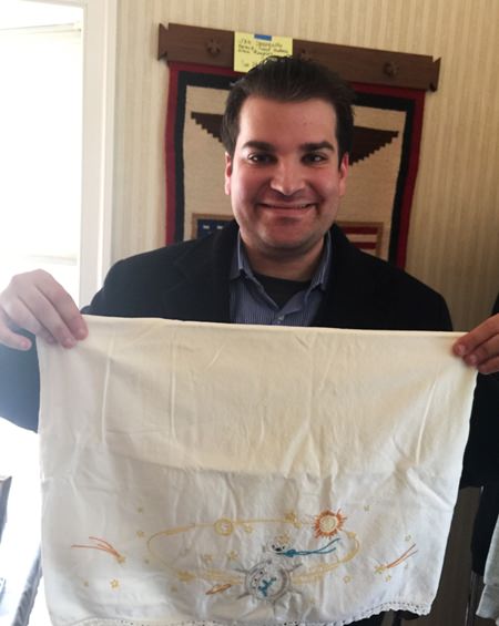 Adam Sackowitz holds up an embroidered pillowcase with celestial bodies on it that belonged to the late John Glenn (Courtesy of Adam Sackowitz via AP)