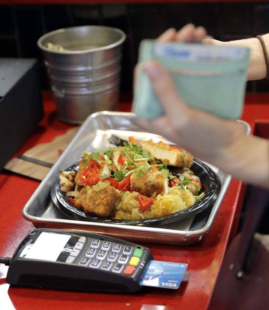 In this Tuesday, April 10, 2018, photo, a customer uses a credit card machine to pay for food at Peli Peli Kitchen in Houston. (AP Photo/David J. Phillip)