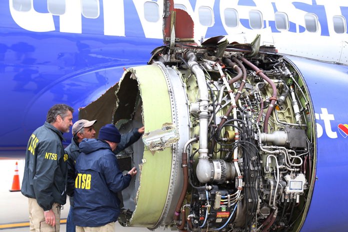 National Transportation Safety Board investigators examine damage to the engine of the Southwest Airlines plane that made an emergency landing at Philadelphia International Airport in Philadelphia on Tuesday, April 17, 2018. (NTSB via AP)