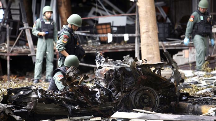 In this August 24, 2016 file photo, bomb squad officers examine the wreckage of a car after an explosion outside a hotel in Pattani province, southern Thailand. (AP Photo)