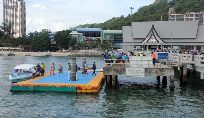 Tourists make their way down from the pier to the pontoon to board a speedboat.