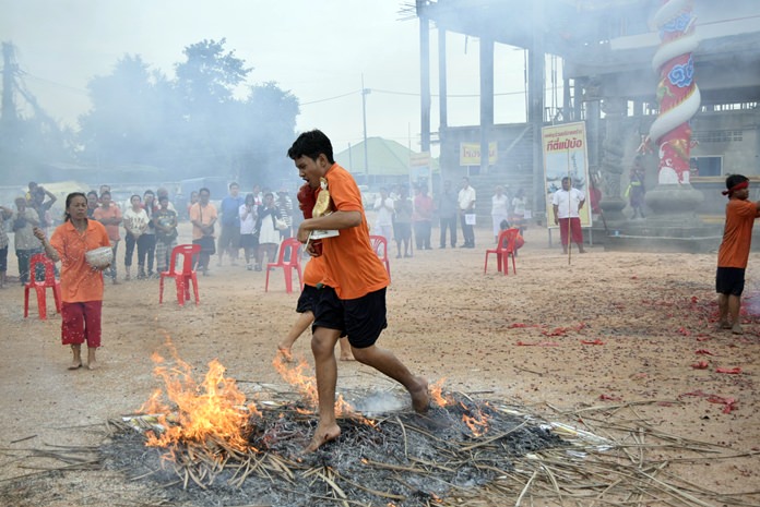 A devotee walks barefoot over a bed of hot embers as he carries an image of Chao Mae Lim Kor Niew during the annual festival to honor the goddess of fire and water. It is believed that the ritual purifies the participants, proves their faith and fulfills their vows and helps ward off evil spirits while praying for luck and good fortune. 