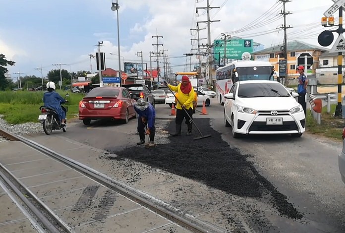 Workers patch the road surface at the railway tracks on SCC Road.