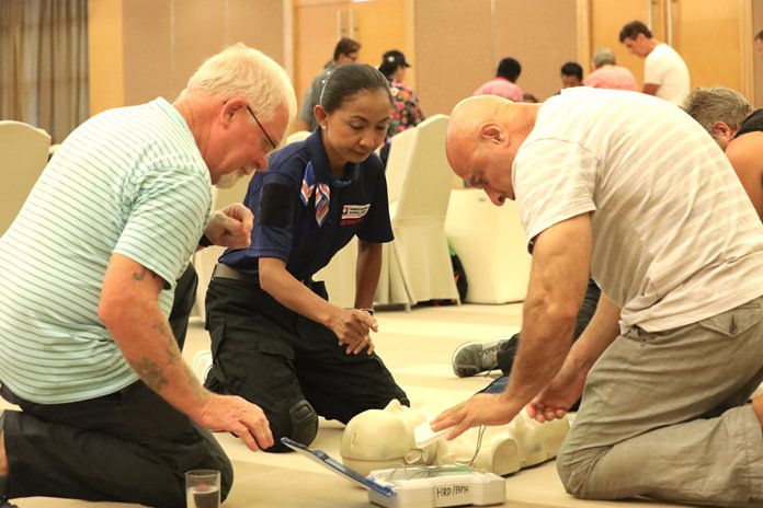 Two PCEC members learn how to use an AED device on the practice dummy.