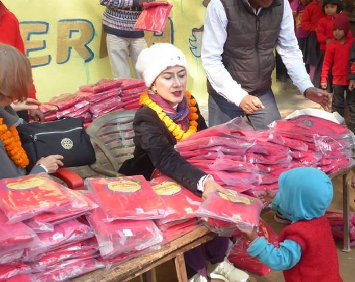 Maneeya Engelking distributes sweaters to children in the village.