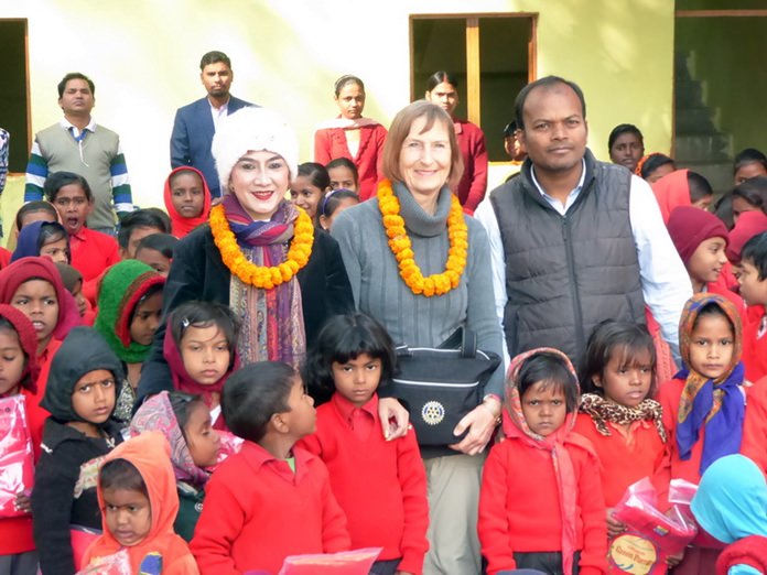 Maneeya and Dr. Margret pose with the happy children wearing their new red sweaters.