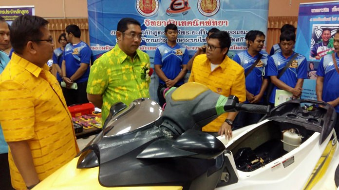 An instructor shows Sontaya Kunplome a jet ski undergoing repairs.
