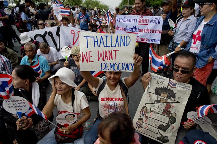 Pro-democracy supporters stage a sit-in protest in front of a police line during a gathering to mark the fourth anniversary of the military take-over of government in Bangkok, Tuesday, May 22. (AP Photo/Gemunu Amarasinghe)