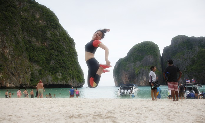 A tourist jumps for a photo on the popular beach at Maya Bay on Koh Phi Phi Leh.