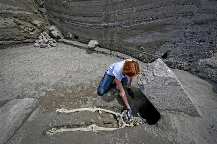Anthropologist Valeria Amoretti works with a brush on a skeleton of a victim of the eruption of Mt. Vesuvius in A.D. 79, which destroyed the ancient town of Pompeii, at Pompeii' archeological site, near Naples, on Tuesday, May 29, 2018. The skeleton was found during recent excavations and is believed to be of a 35-year-old man with a limp who was hit by a pyroclastic cloud during the eruption. (Ciro Fusco/ANSA via AP)