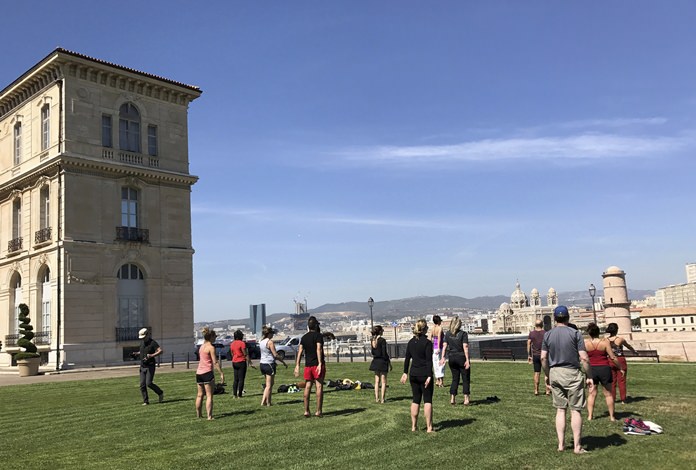 Guests from a Regent Seven Seas cruise perform tai chi outdoors on a port call in Marseille, France, with a view of the sea. (Harrison Liu via AP)