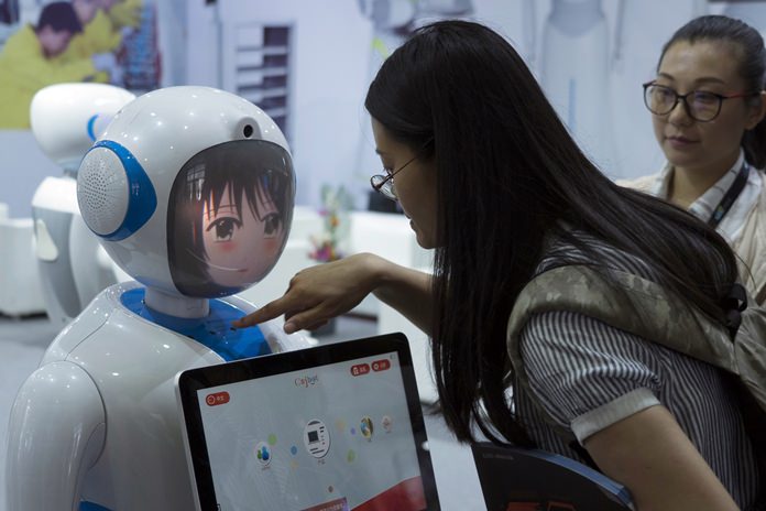 Women interact near a robot designed by Chinese robotics company Pangolin at the Consumer Electronics Show Asia 2018 in Shanghai, China on Friday, June 15. President Donald Trump is hiking the price of Chinese-made forklift trucks and X-ray machines for American buyers. They are part of a $50 billion list of Chinese exports targeted for a 25 percent tariff hike in response to complaints Beijing steals or pressures foreign companies to hand over technology. (AP Photo/Sam McNeil)