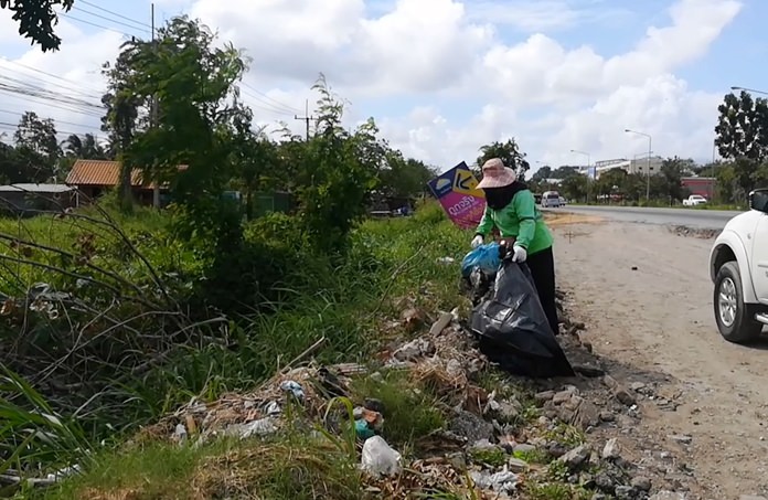 Nong Plalai public health workers clean up roadsides littered with trash following heavy rain.