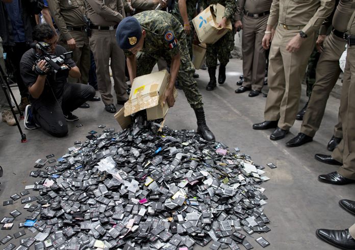 Law-enforcement officers unload boxes full of mobile batteries during a raid at a factory accused of importing and processing electronic waste in the suburbs of Bangkok, Thursday, June 21. (AP Photo/Gemunu Amarasinghe)