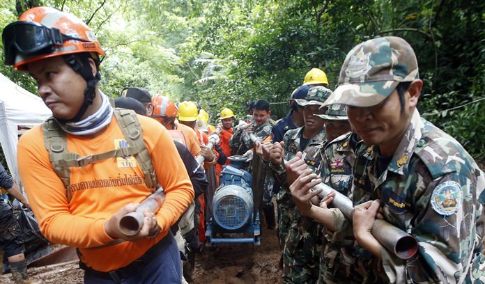 Rescue personnel drag a water pump up to the flooded cave that a soccer team and their coach are believed to be missing in, Thursday, June 28, 2018.(AP Photo/Sakchai Lalit)